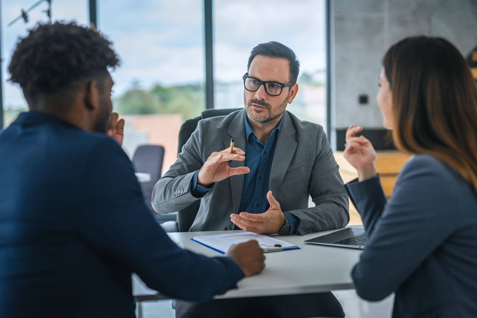 An adviser talking through paperwork with two clients across a desk
