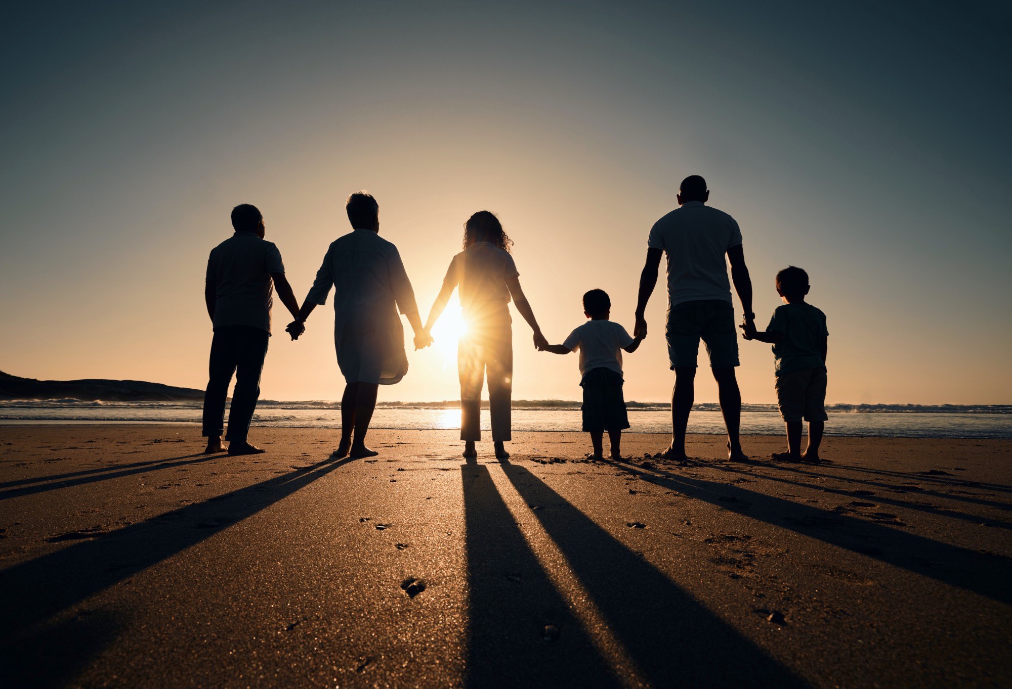 A family holding hands on the beach at sunset