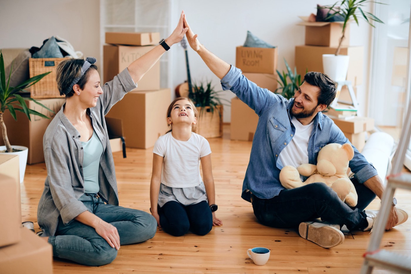 Parents making a roof shape with their hands over their daughter in their new home