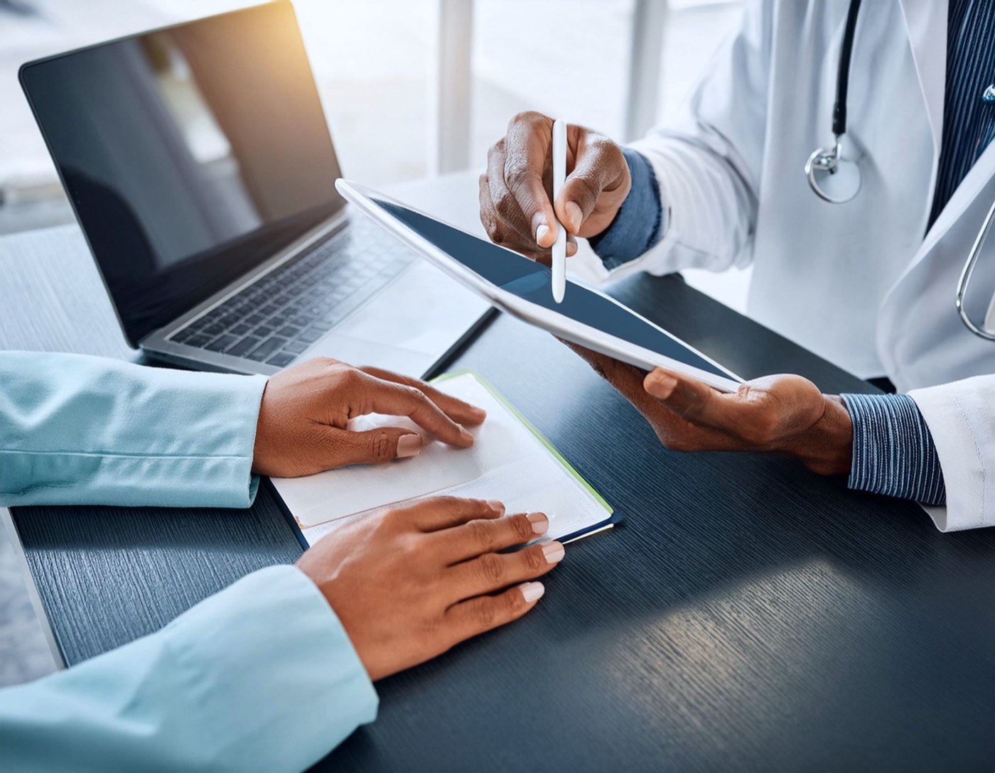 A doctor showing a patient information on a tablet across a desk